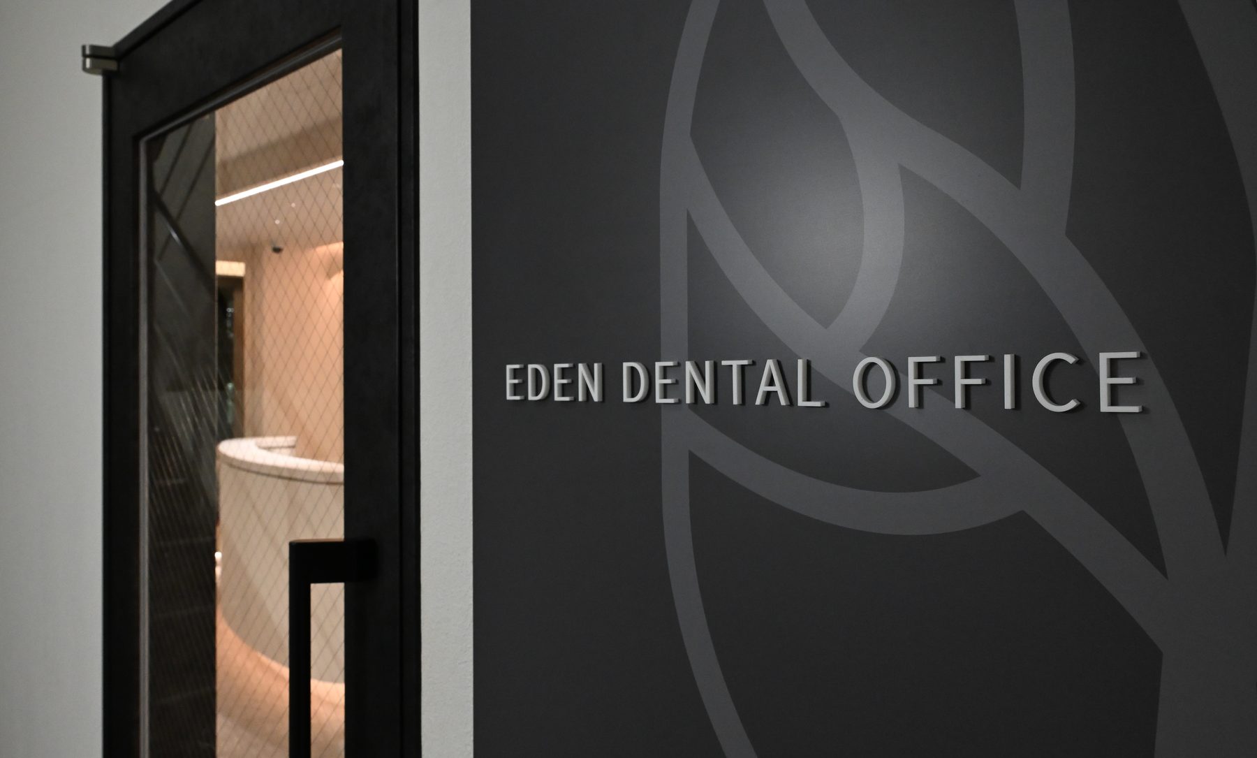 Eden Dental Office entrance on the 4th floor with logo on dark wall