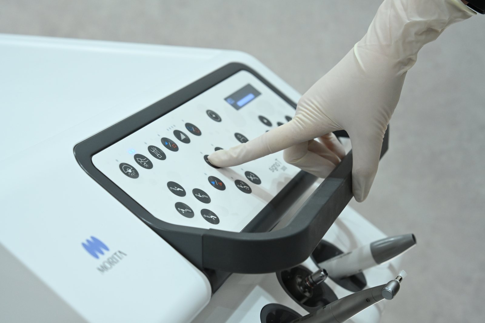 Gloved hand on a Morita dental unit control panel — modern equipment at Eden Dental Office Nagoya